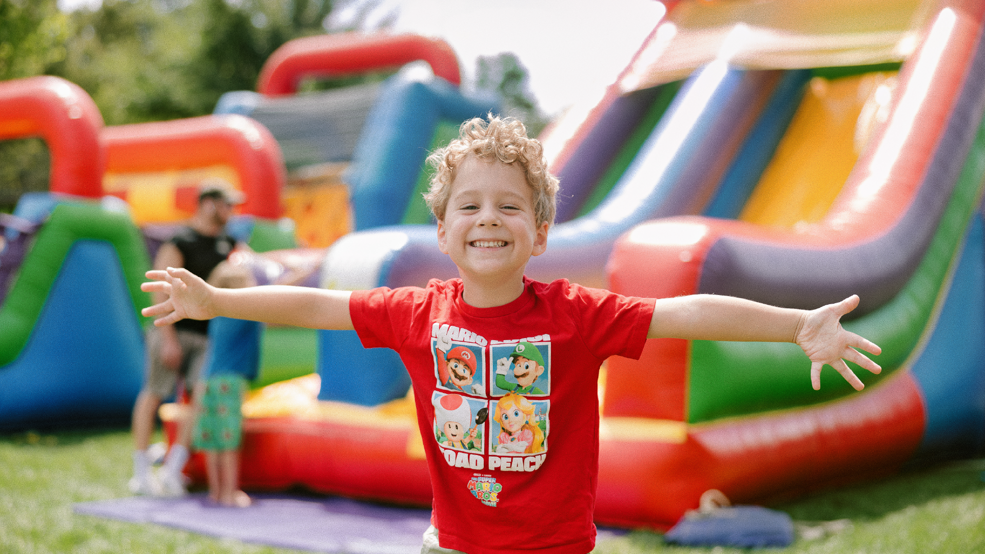 A young child runs with arms open in front of an inflatable slide at Dorrian Days - Photo Credit: Robb McCormick Photography