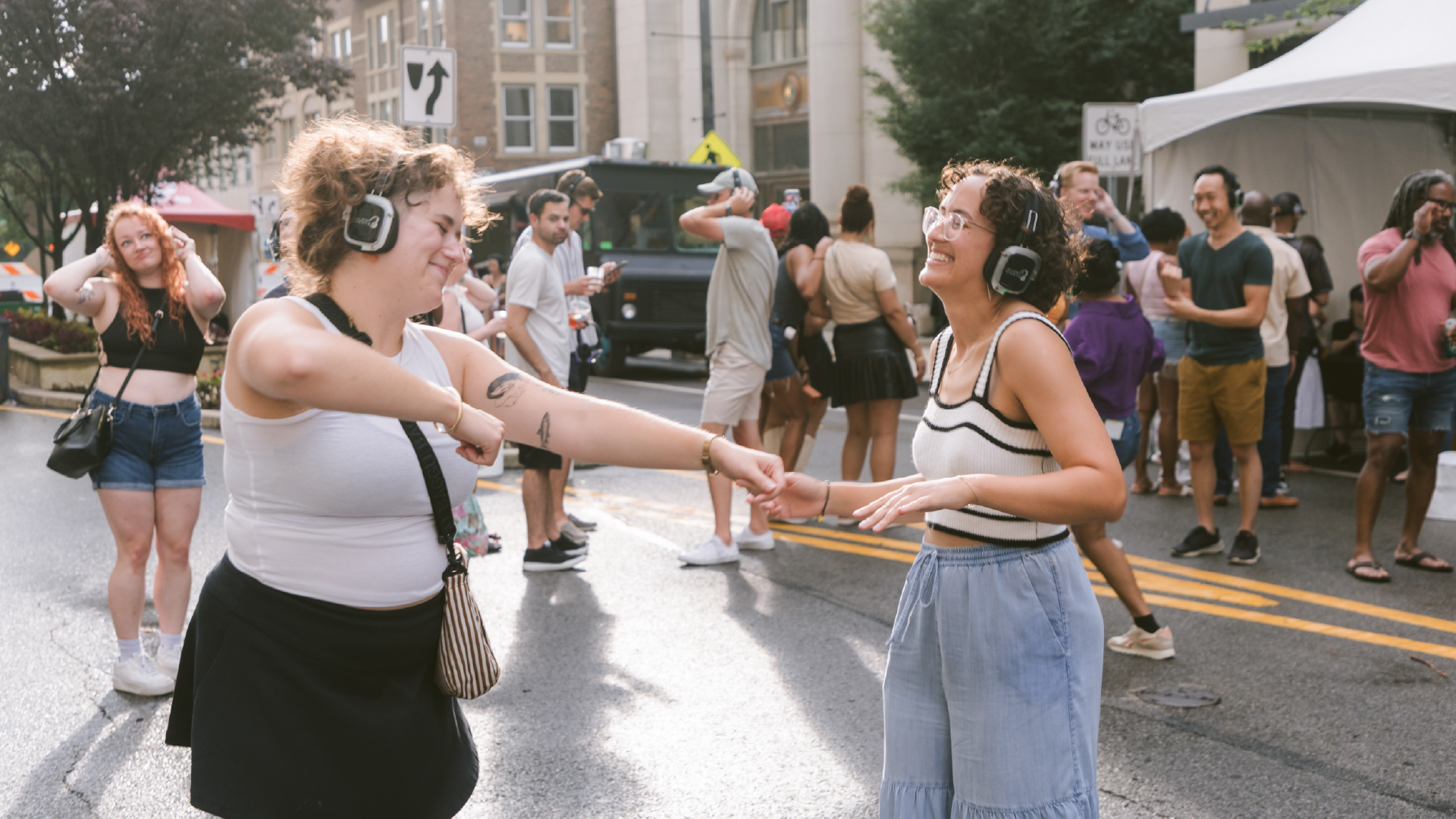 Two people wearing headphone and dancing at a silent disco dance party.