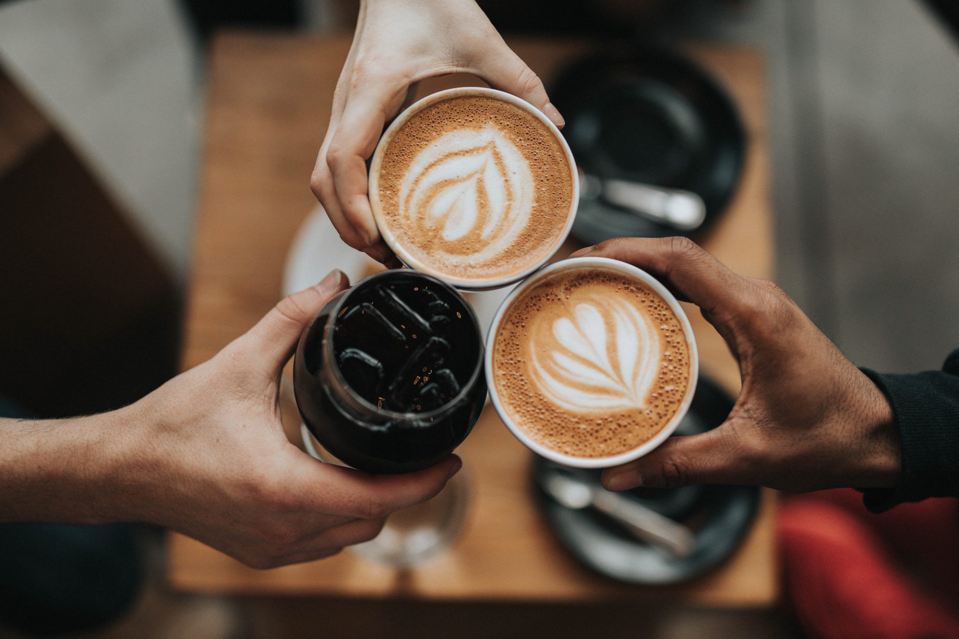 Three coffee mugs with latte art foam on top.