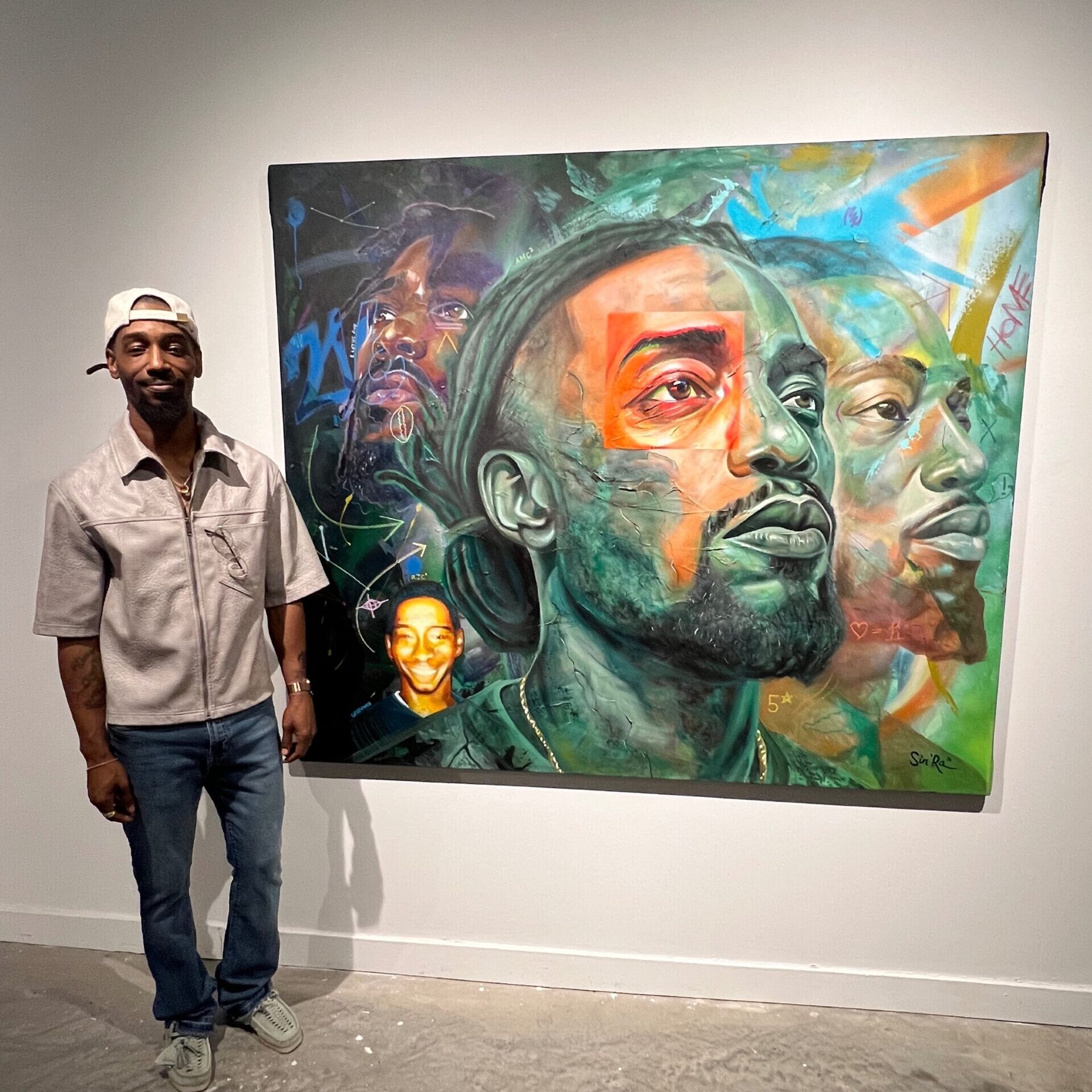 Photo of Arris Cohen standing next to his artwork